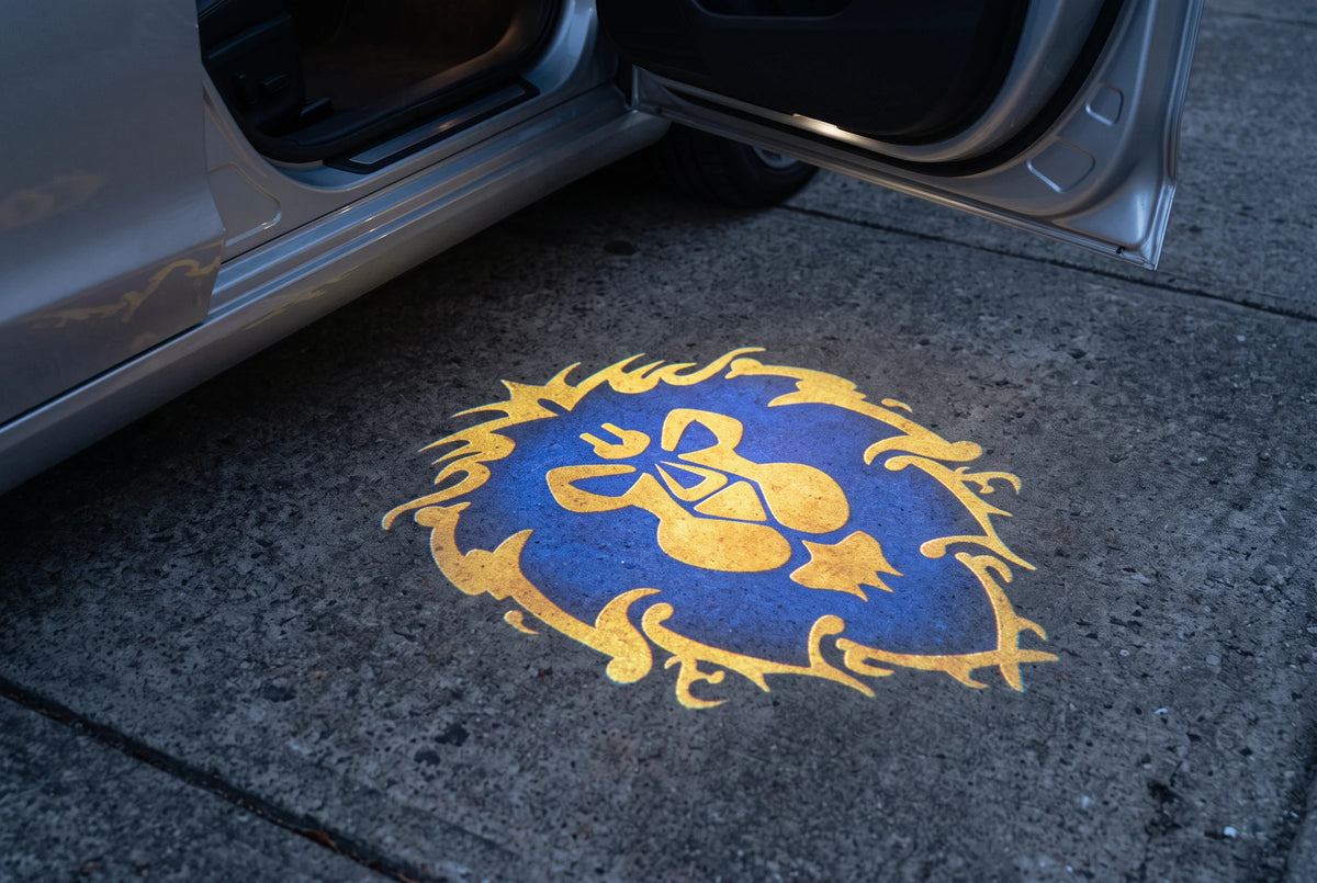 Blue and gold Alliance projection beside a silver car on a driveway