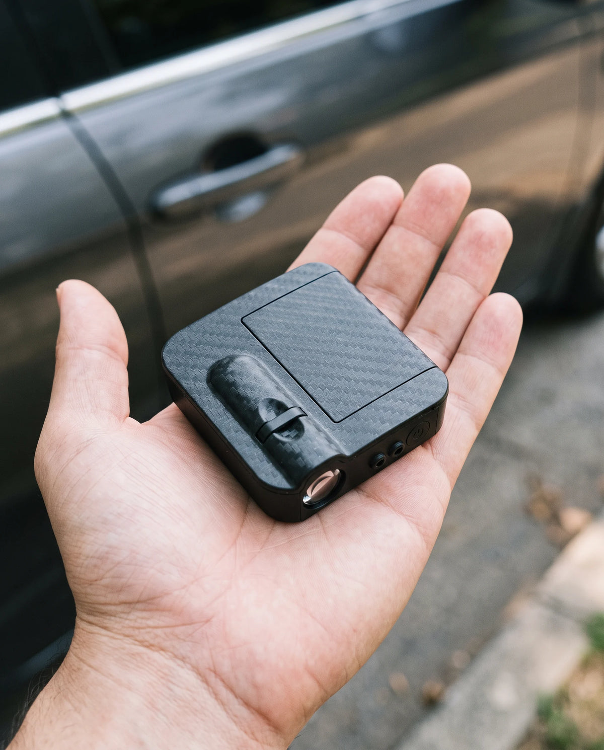 The compact projector resting in an adult palm for scale
